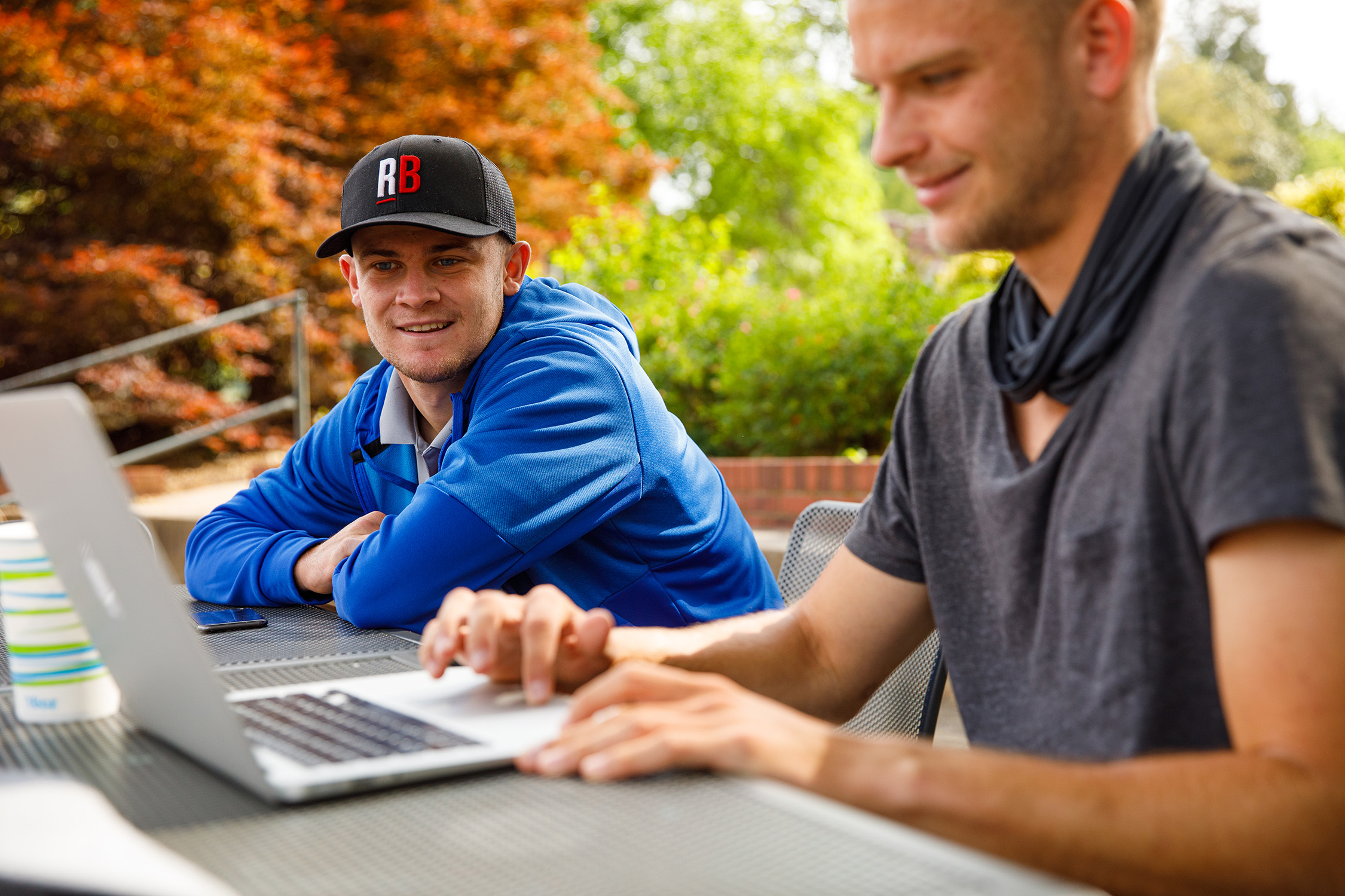 Male students outside on a computer